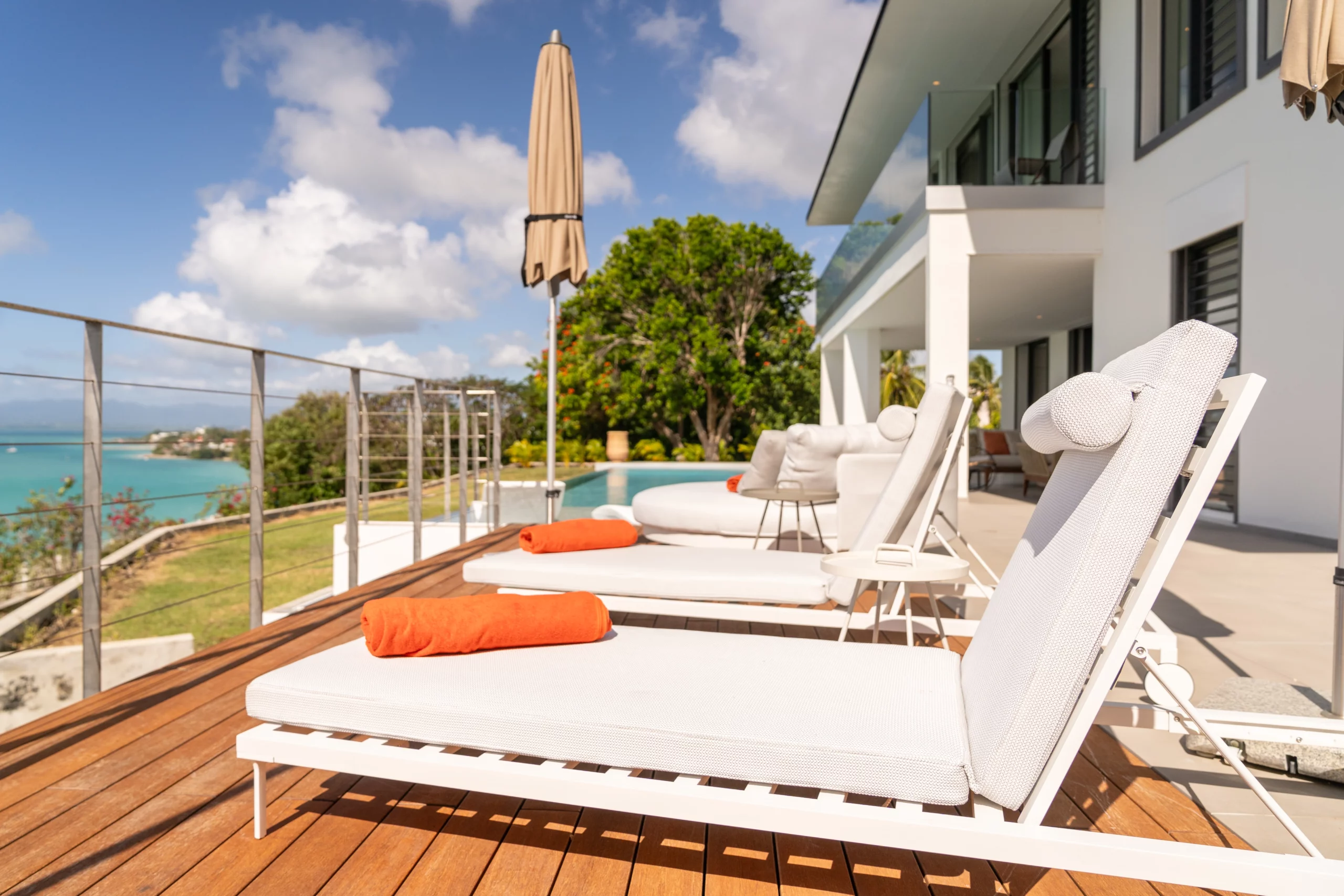 transats à côté d'une grande piscine dans une villa vue mer en guadeloupe