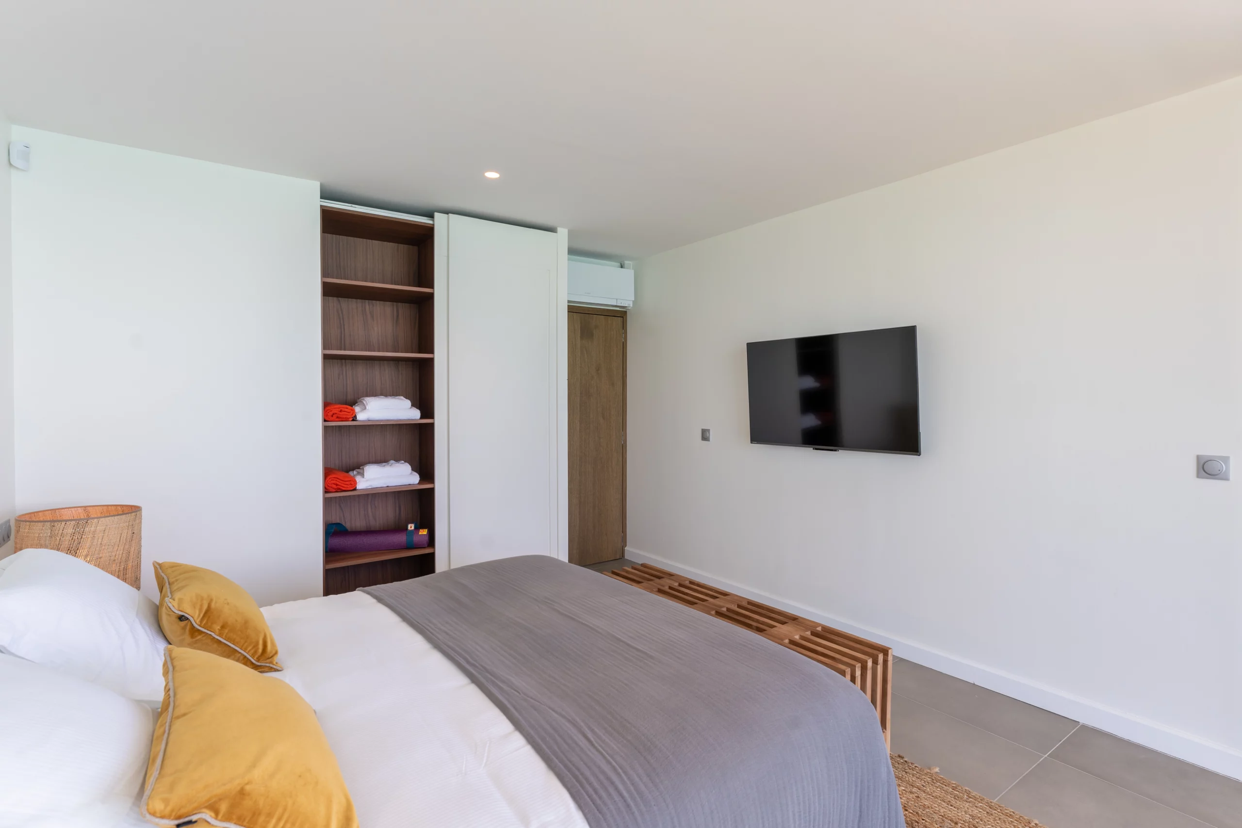 chambre double avec dressing ouvert laissant apparaître des tapis de yoga et des serviettes de bain