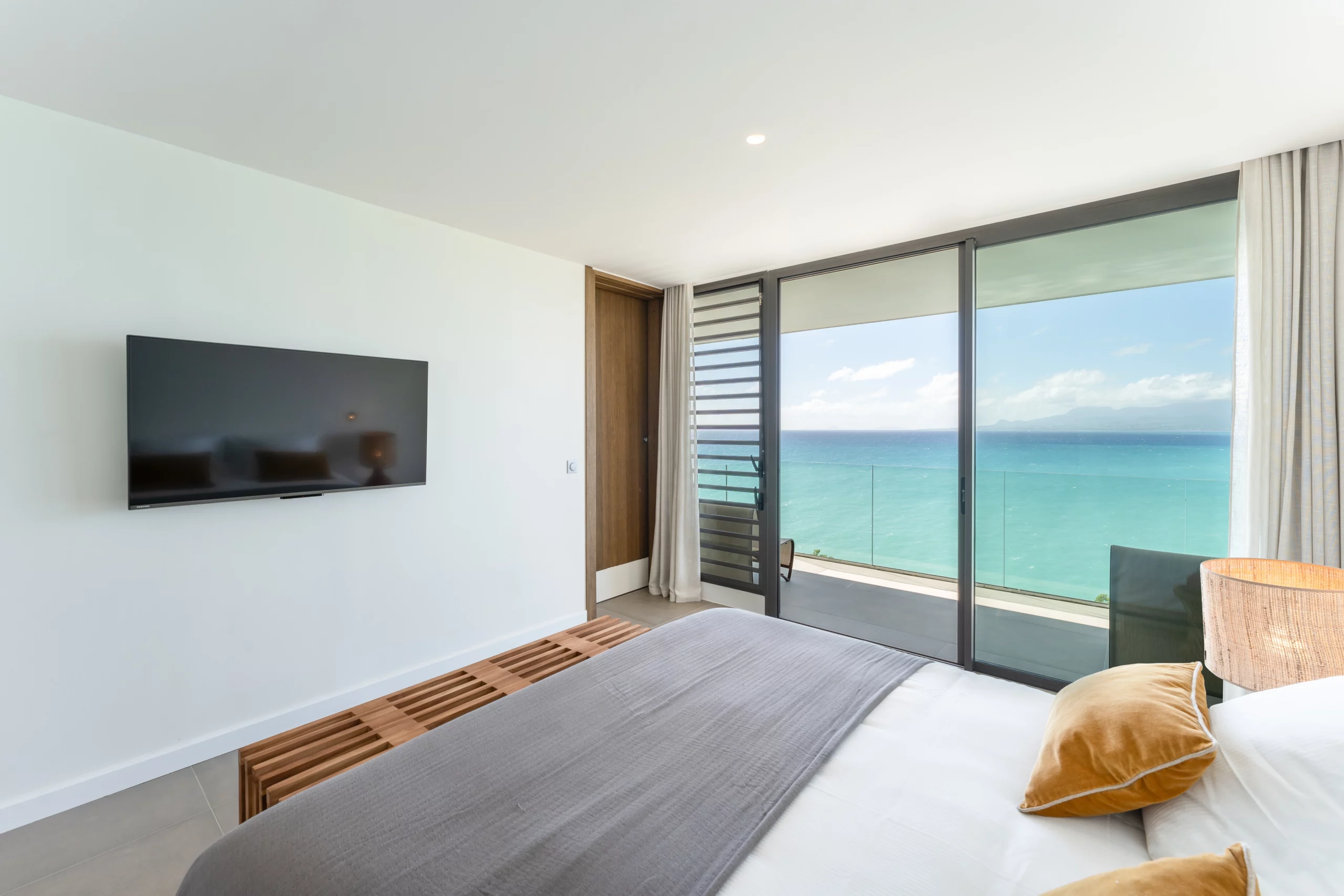 suite de luxe vue mer avec smart TV et oreillers jaunes dans une villa avec piscine en guadeloupe